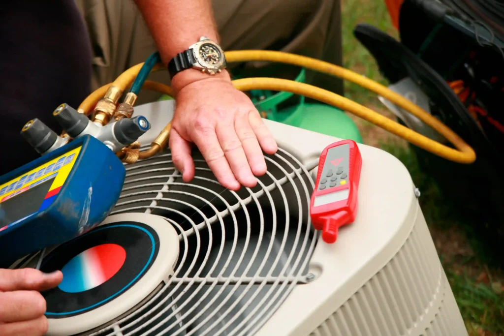 HVAC University in Place, WA 1 A close-up of a technician's hand and tools, including a pressure gauge, on top of an outdoor AC unit.