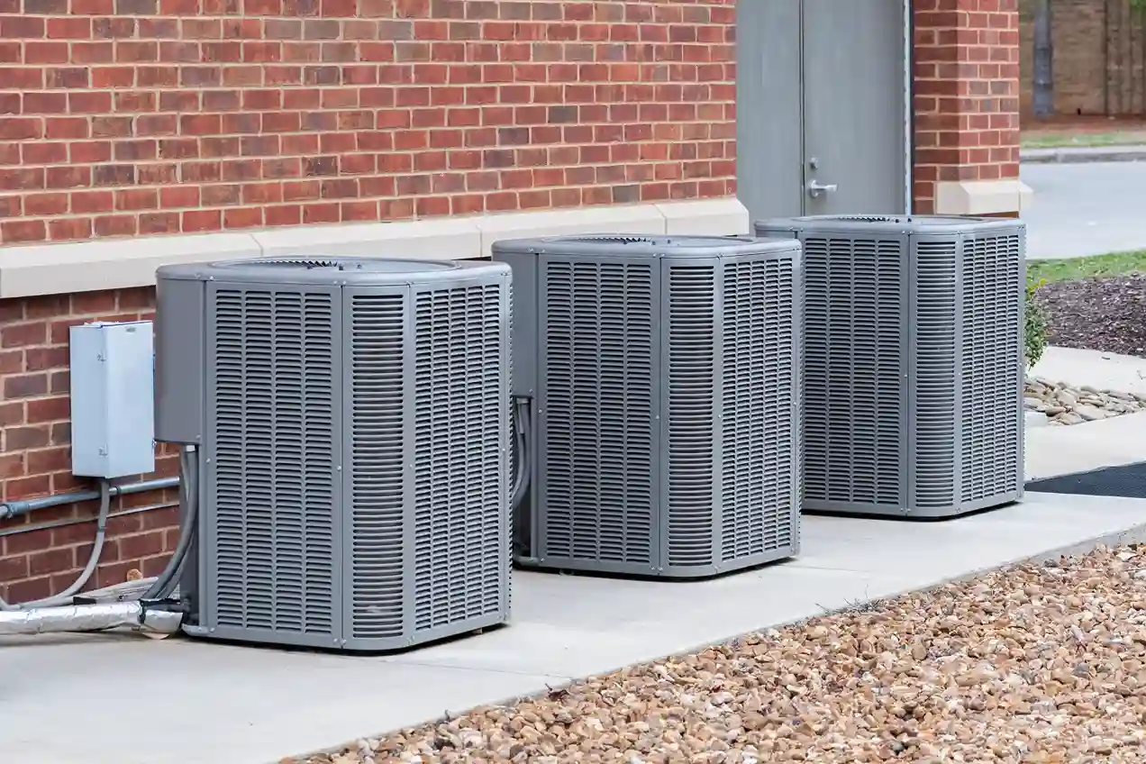 AC Service and Maintenance in Bucoda, WA 1 Three large, gray outdoor air conditioner units are installed in a row next to a brick building.