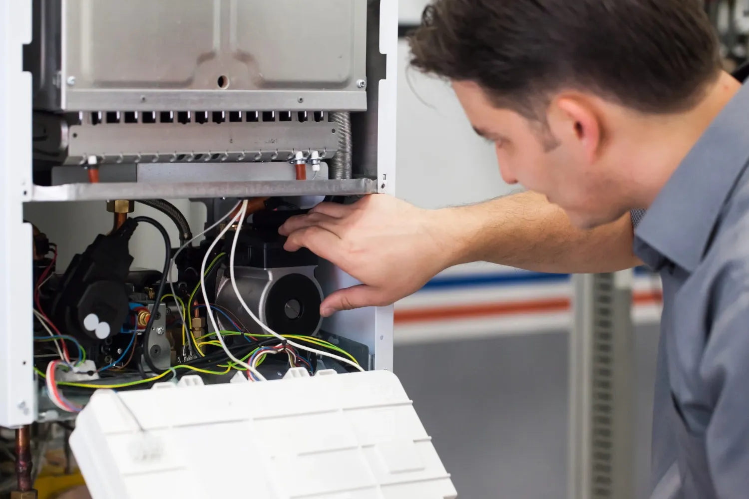 A close-up of a service technician performing maintenance on the internal components of a furnace unit.