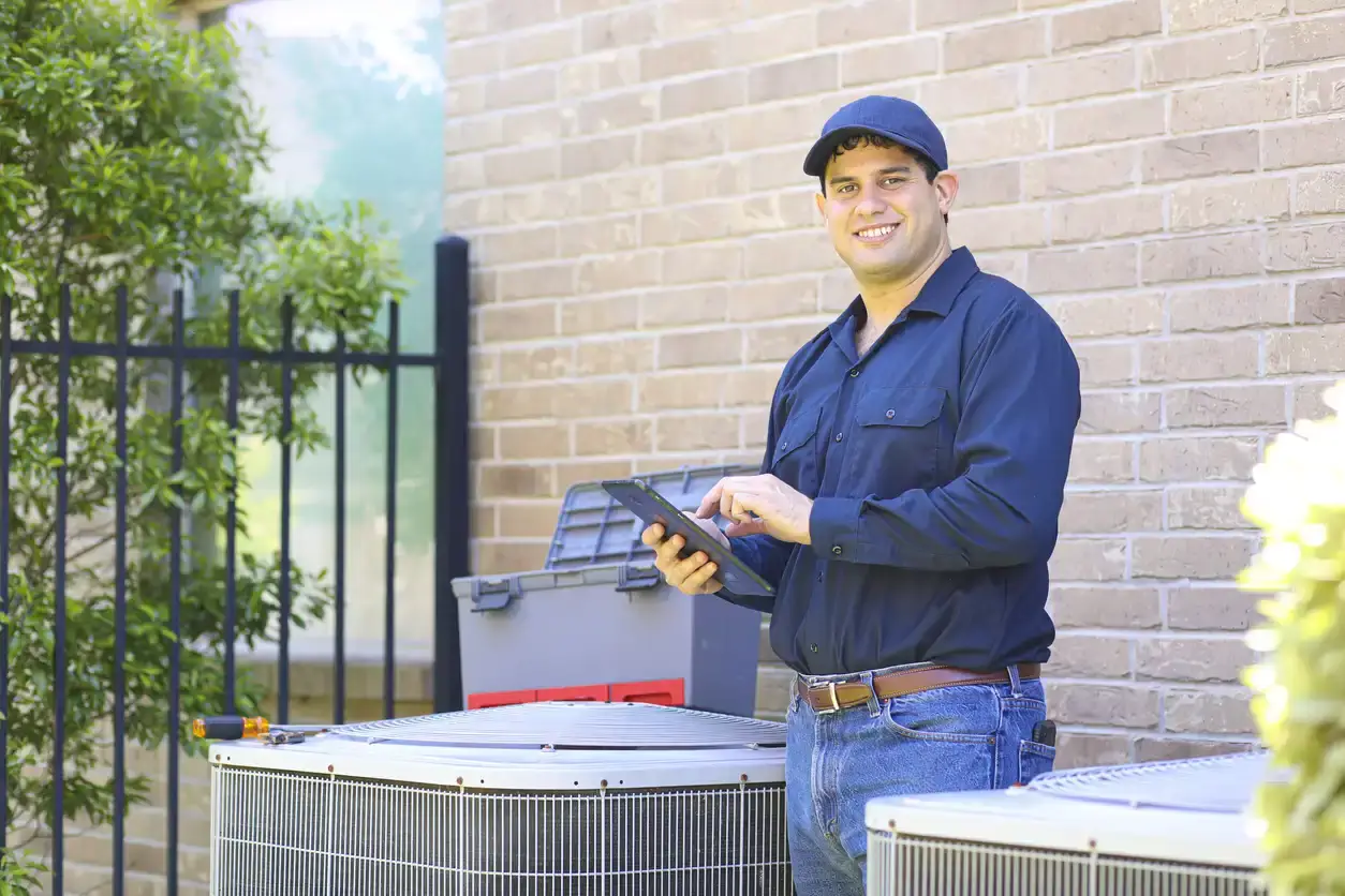 HVAC (Heating, Ventilation, and Air Conditioning) technician performing service or inspection work on an outdoor condensing unit, likely an air conditioner or a heat pump.